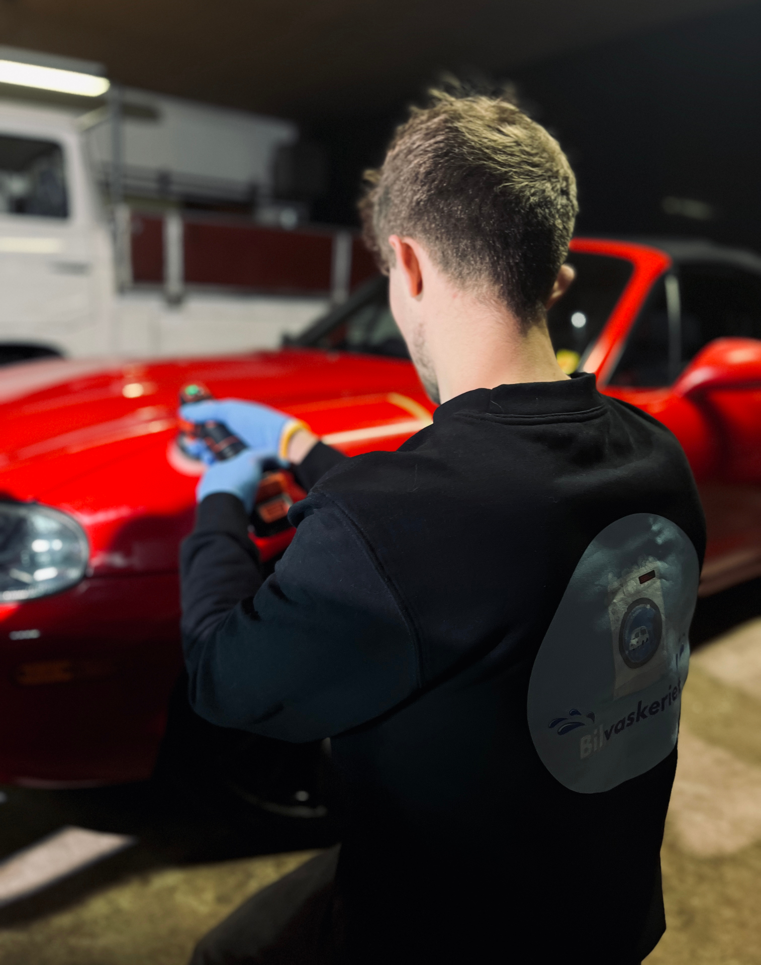 Bilvaskeriet polerer en rød Mazda MX-5 i værkstedet